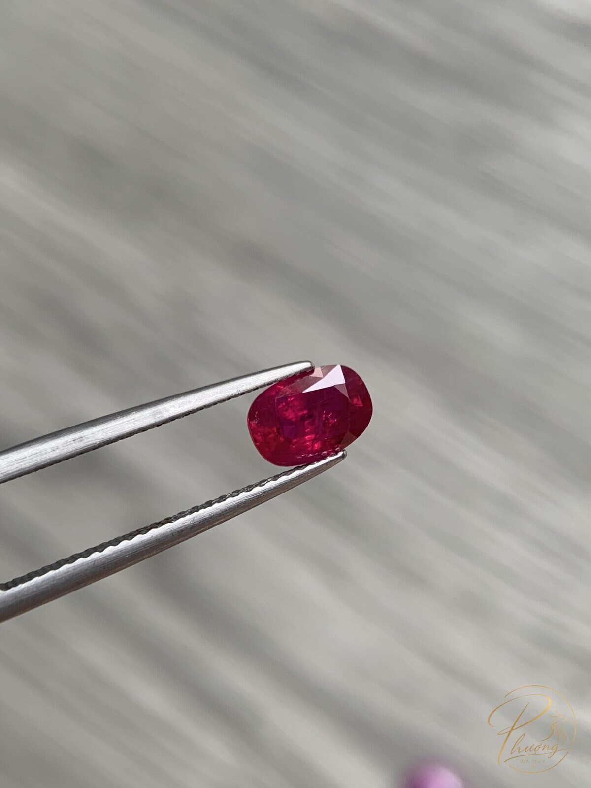Viên ruby facet màu đỏ đậm trên kẹp gắp, đá cứng 9 Mohs hợp mệnh Hỏa
