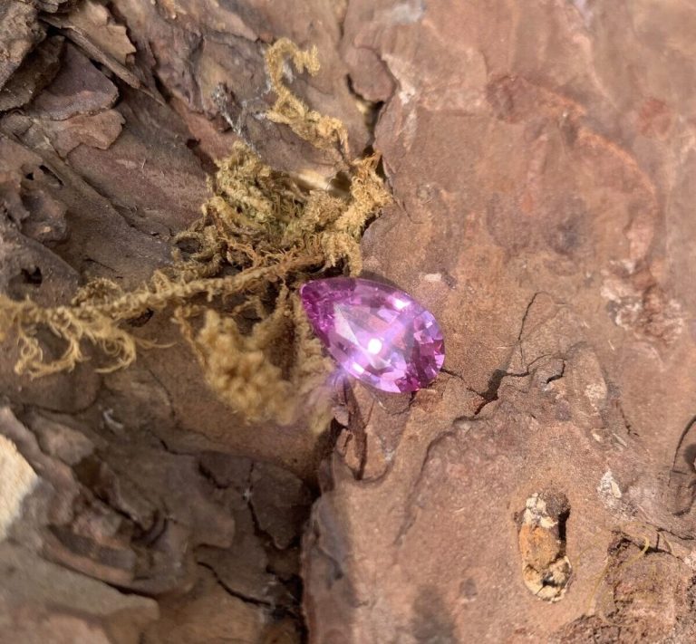 Viên spinel hồng tím tự nhiên dáng pear, nguồn gốc Lục Yên, đặt trên nền vỏ cây