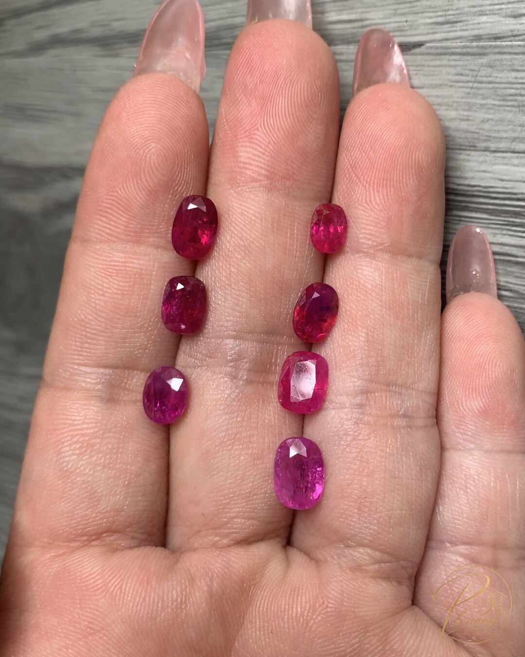 7 viên ruby rời với sắc độ đỏ và kích thước khác nhau đặt trên tay