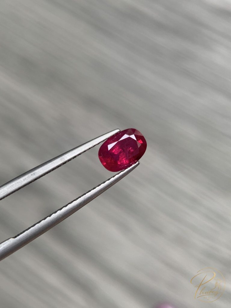 Ruby là gì - viên ruby tự nhiên mài giác oval màu đỏ đậm, giữ trên kẹp gắp