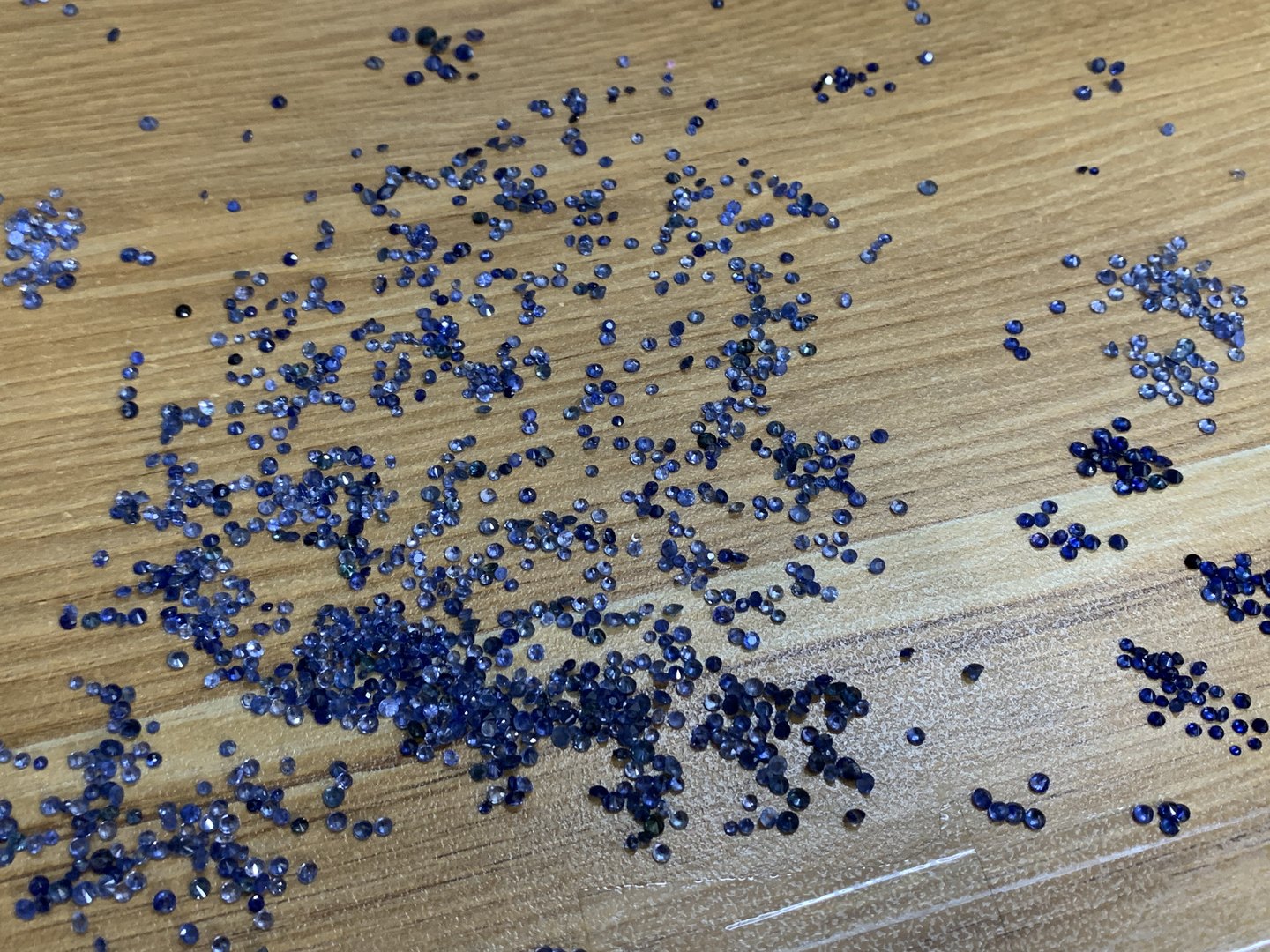 lô sapphire lam cỡ nhỏ giác tròn rải trên mặt bàn gỗ