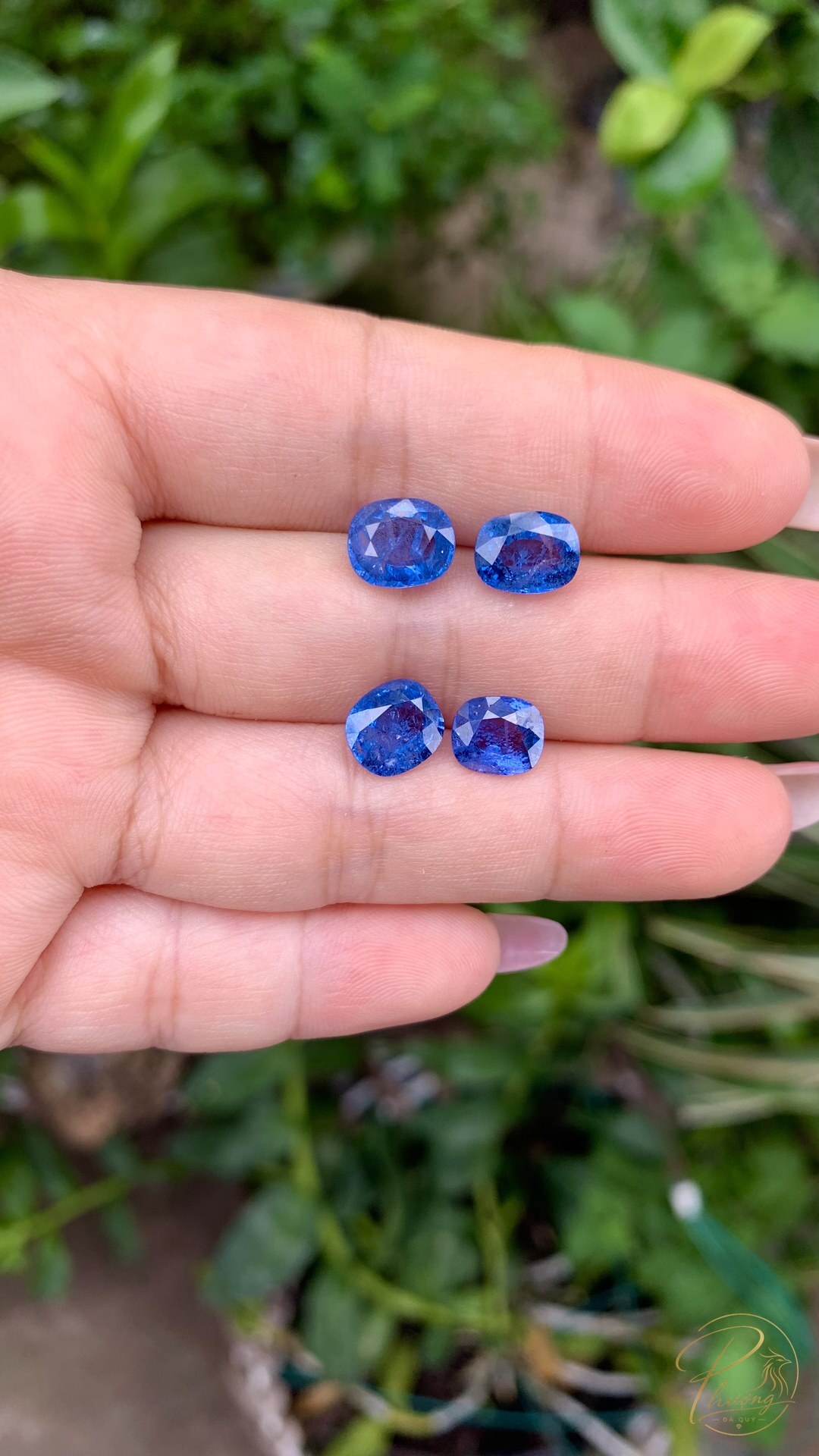 bốn viên spinel xanh cobalt đặt trên ngón tay để so kích thước