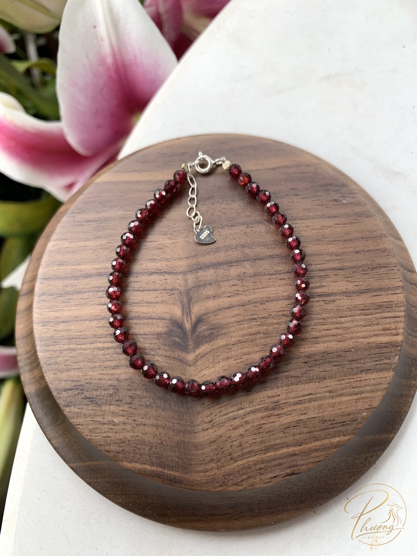 Lắc tay Garnet đỏ mài giác tự nhiên trên đế gỗ, minh hoạ độ cứng Mohs khi đeo hằng ngày