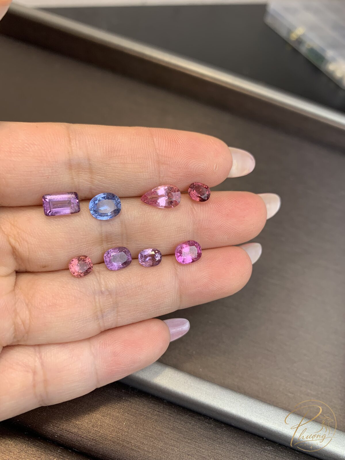Tám viên Spinel tự nhiên mài giác màu tím, lam nhạt, hồng và hồng cam trên ngón tay